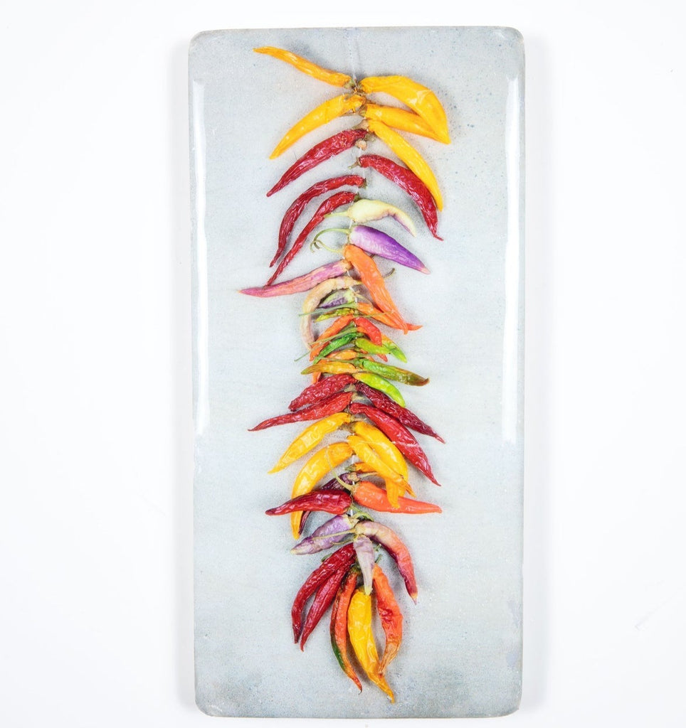 Strings of coloured chili peppers on grey